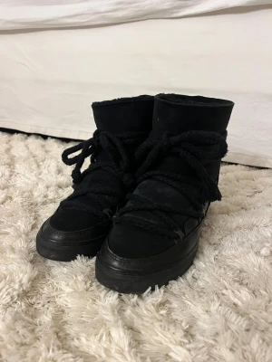 Inuikii vinterskor - Vinterskor från Inuikii i svart, skorna har klack i sig så du blir längre när du har på dig dom. Utsidan är i mocka och skinn, med mjukt foder på insidan. Snyggt chunky utseende och högt skaft, perfekt för kalla dagar. Inuikii-logga på hälen och robust design. Defekter på insidan av skorna: se bilder