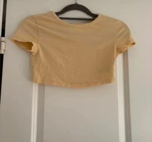 Beige croppad topp från DIVIDED - Säljer en enkel och snygg croppad topp från DIVIDED i storlek S. Toppen är beige, har rund hals och korta ärmar. Tillverkad i mjuk bomull som är skön mot huden. Perfekt att matcha med jeans eller kjol för en chill look.