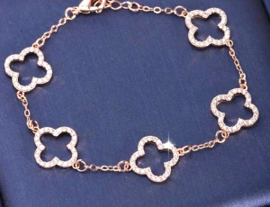 Guld rosa färg armband med glittriga fyrklöver - Superfint armband i guldton med fem fyrklöverformade länkar, täckta av små glittrande stenar. Kedjan är tunn och elegant, perfekt för att ge lite extra bling till din stil. Lås med karbinhake för enkel användning.