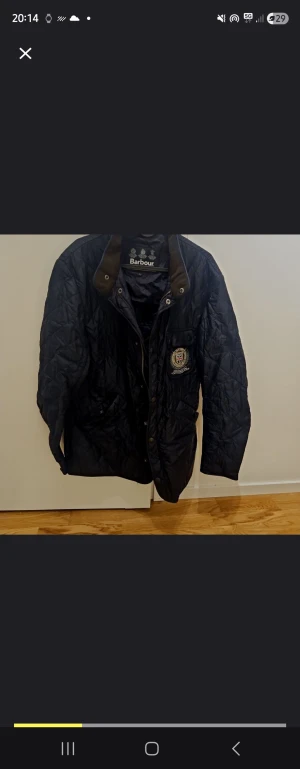 Svart quiltad Barbour jacka herr L - Quiltad svart jacka från Barbour i storlek L. Klassisk modell med bröstficka, broderad logga och tryckknappar. Jackan har lång ärm, krage i kontrastfärg och är tillverkad i polyester. Perfekt för höst och vår. Finns en liten reva som syns i sista bilden. 