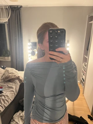 Ljusblå offshoulder långärmad topp - Säljer en ljusblå långärmad topp med offshoulder-skärning och lätt rynkade detaljer vid axlarna. Toppens material är mjukt! 
