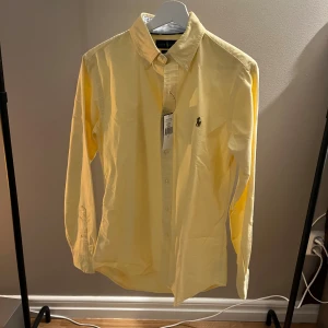 Ralph Lauren Skjorta - Tja! Säljer en riktigt snygg Ralph Lauren skjorta. Den är helt ny med lappen kvar . Skjortan är i färgen  gul. Storlek S kan passa M. Den är perfekt till våren och sommaren☀️ Nypris runt 2000 kr Hör av dig vid funderingar🙌