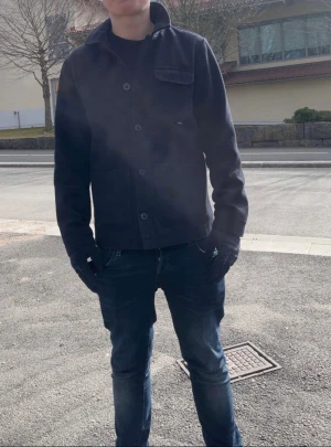 Mörkblå overshirt med knappar - Snygg mörkblå overshirt med klassisk krage och stora knappar framtill. Jackan har en bröstficka med lock och två sidofickor, perfekt för en chill och stilren look. Materialet känns mjukt och passar bra till jeans eller chinos. Märke: casual friday 