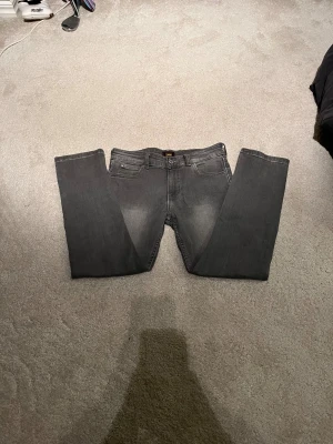 Grå jeans från Lee, storlek 10-11Y - Snygga grå jeans från Lee med klassisk femficksdesign och raka ben. Jeansen har en neutral grå färg och är tillverkade i mjukt bomullsmaterial. Passar dig som gillar enkel och stilren look. Perfekt för dig som vill ha ett par jeans som funkar till det mesta. Nästan oanvända 