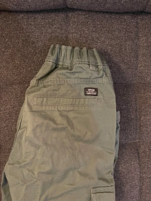 Gröna cargopants stl 158 - Snygga gröna cargopants från Kappahl med elastisk midja och fickor på benen. Användes endast 1 gång.