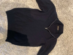 Svart stickad half zip från Oscar Jacobson - Svart stickad tröja från Oscar Jacobson med half zip-dragkedja i halsen. Tröjan har långärmade ribbade muddar och en hög krage som ger en clean och stilren look. Perfekt för dig som gillar klassisk stil med en modern twist.Pris kan diskuteras!