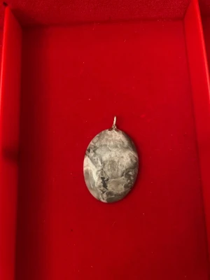 Gråmarmorerad oval halsbandshänge - Snyggt ovalformat halsbandshänge med gråmarmorerat mönster. Hängsmycket har en neutral färgskala i grått och silver, vilket gör det lätt att matcha med olika kedjor. Perfekt för dig som gillar stilrena och unika accessoarer. 