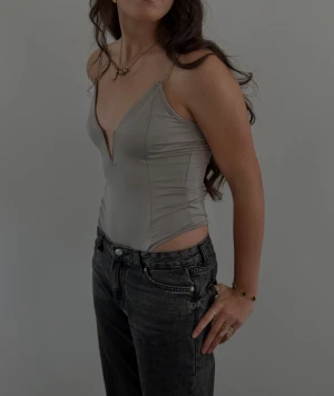 Snygg fest body - Säljer en snygg fest body. Bodyn har en figurnära passform och är tillverkad i ett slätt, syntetiskt material som ger en snygg siluett. Perfekt att styla med jeans eller kjol inför en perfekt utekväll.