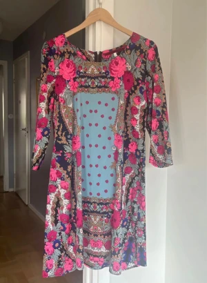 Klänning från RoseBud / Sukienka RoseBud - Blommig klänning i starka färger från RoseBud. Trekvartsärm, dragkedja bak. I mycket bra skick storlek S