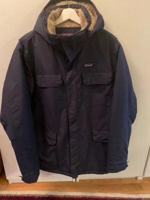 Mörkblå parkajacka Patagonia XL - Säljer min blå Patagonia Isthmus Parka i storlek XL. Jackan är varsamt använd och i mycket fint skick. Den är varm, bekväm och perfekt för höst, vinter och tidig vår. Modellen har ett klassiskt längre snitt, bra vind- och vattenavvisning samt flera praktiska fickor. Jackan har dessutom en avtagbar huva och ett mjukt innerfoder som gör den skön även under riktigt kalla dagar. 