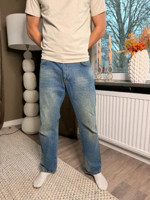 Woodbird  ljusblå jeans straight fit - Säljer ett par klassiska Woodbird jeans i ljusblå tvätt med snyggt slitna detaljer. Modellen har rak passform, normal midja och fem fickor. Jeansen är tillverkade i robust denim och har den ikoniska läderpatchen bak i midjan.