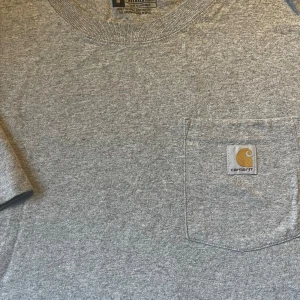 T-shirt Carhartt - Grå Carhartt T-shirt med bröstficka Strl M, lite stor i storlek Sparsamt använd pga fel storlek 