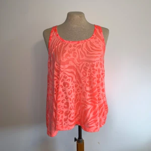 Neonlinnen med djurmönster - Två coola linnen i neonrosa och neongult med transparent känsla och djurmönster som mixar zebra och leopard. Modellen är lös och ärmlös med brottarrygg, perfekt för att sticka ut på sommaren eller till träning. Materialet känns lätt och luftigt. Ena är storlek S och andra är storlek M, men passformen är ganska lik bara längden som är annorlunda 