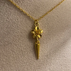 Guldigt halsband med blomma och spike - Unikt halsband i guldton med en kedja och ett hänge som kombinerar en detaljrik blomma och en cool spike