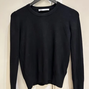 Svart stickad tröja med guldknappar Zara - Svart stickad tröja från Zara i storlek S. Tröjan har rund halsringning, långa ärmar och snygga guldknappar vid ärmsluten som ger en extra touch. Perfekt för dig som gillar stilrena och enkla plagg med en twist.