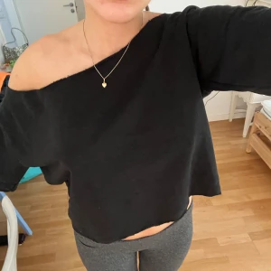 Svart offshoulder topp - Svart topp med offshoulder-design och korta ärmar. Toppens enkla stil gör den lätt att matcha. Tyget är liknande hoodie tyg vilken gör den perfekt nu till hösten. 
