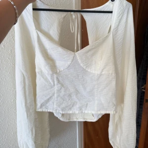 Vit croppad blus från Gina Tricot - Superfin creme vit croppad blus med långa puffärmar och snygg v-ringning från Gina Tricot som inte kommer till användning. Storlek M. 