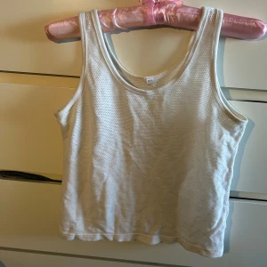 Vit mesh linnetopp  - Säljer en vit mesh-linnetopp. Toppen är ärmlös och har en sportig vibe med sitt luftiga, perforerade tyg. Perfekt för varma dagar eller lager på lager. Enkel och stilren design som passar till mycket.