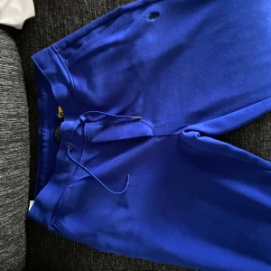 Blå mjukisbyxor från Polo Ralph Lauren - Snygga blå mjukisbyxor från Polo Ralph Lauren med dragsko i midjan och bakficka. Sköna och stilrena, perfekta för chill eller streetwear. Tillverkade i mjukt bomullsmaterial för maximal komfort.