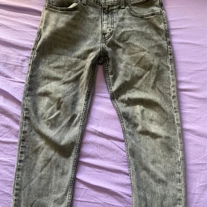 Levi's 502 grå jeans W30 L32 - Säljer ett par Levi's 502 Hi-Ball jeans i grå tvätt. Klassisk femficksmodell med raka ben och normal passform. Jeansen har snyggt slitna detaljer och är tillverkade i bomull. Perfekta för dig som gillar en avslappnad men stilren look.