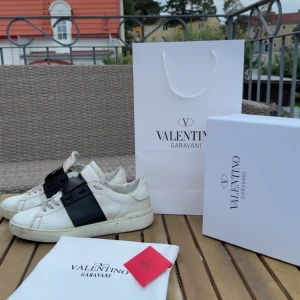 Valentino Garavani Open sneakers vit/svart - Säljer ett par snygga Valentino Garavani Open sneakers. Litet litet hål under skon alltså Inte topp skick därav priset!! Kommer med originalpåse, box, dustbag och kort. Perfekta nu till vintern, storlek 43 priset är inte spikat så kom med bud eller frågor😊