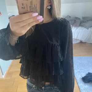 Svart volangblus från Gina  - Supersnygg svart blus från Gina Tricot med volanger. Den sitter ungefär som xxs/xs
