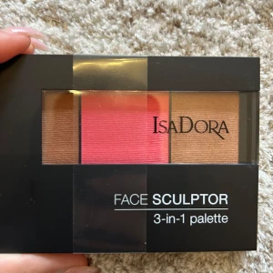 Isadora Face Sculptor 3-in-1 palette - Face Sculptor 3-in-1 palette från Isadora i färgen 64 Intense Peach. Paletten innehåller tre puderprodukter: en varm brun contour, en intensiv persikofärgad rouge och en gyllene highlighter. Perfekt för att skulptera och ge glow till ansiktet. Cruelty free och parfymfri.
