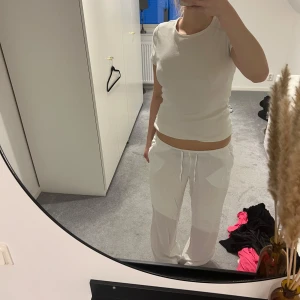 Vita linnebyxor med snörning - Säljer ett par vita linnebyxor med avslappnad passform och dragsko i midjan. Byxorna har raka ben och sidfickor, perfekta för en chill och luftig stil. Superbekväma och lätta att matcha med allt.