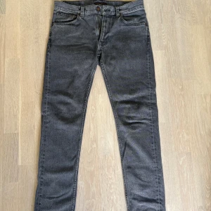 Grå Lean Dean jeans från Nudie Jeans - Säljer ett par gråa Lean Dean jeans från Nudie Jeans i färgen Grey Ash. De har en slim passform med klassisk femficksdesign och snygga bakfickor med broderad detalj. Tillverkade som sale sample därav lite limiterad som kanske inte säljs i vanliga sortimentet. Endast använda några få gånger.