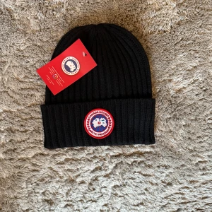 Canada Goose Mössa  - Exklusiv och tidlös mössa från Canada Goose i aa premiumkvalitet. Perfekt för kalla dagar med både stil och komfort. En lyxig accessoar som lyfter varje outfit.  ♦️ Helt ny – originaltag kvar ⚜️ Klassisk & exklusiv design 📦 Snabb leverans & smidig affär 