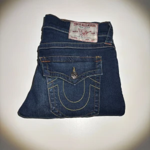 True Religion Jeans herr - Snygga blå jeans från True Religion med ikoniska kontrastsömmar och stora ficklock bak. Jeansen har raka ben, klassisk femficksdesign och detaljerade knappar. Perfekta för dig som vill sticka ut med en streetig look. Använda någon gång ☺️ kan användas av tjejer såklart också eller om man vill sy om till kjol eller liknande😀😀