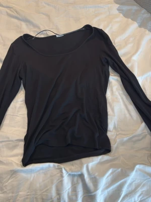 Svart långärmad topp - En enkel svart långärmad topp med rund halsringning. Tunn och mjuk i materialet, perfekt att styla lager på lager eller bära som den är. Passar till det mesta och är ett måste i basgarderoben.