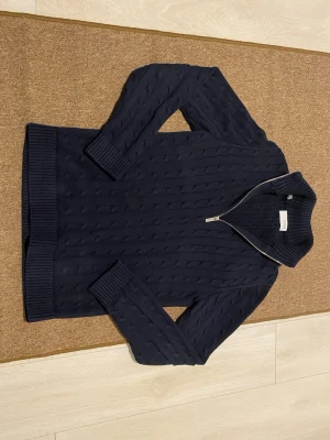 Marinblå cable knit quarter zip -    Ny utan pristag och oanvänd marinblå cable knit quarter zip från Selected Homme. Den klassiska kabelstickningen kombineras med en modern dragkedjekrage för en sofistikerad men avslappnad look. Perfekt för både vardag och arbete, med hög komfort och enkel matchning året runt. Storlek S men passar även Storleken M helt perfekt. Ord pris: 900 kr 