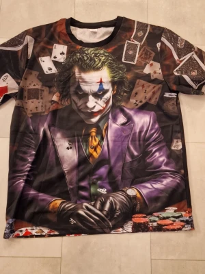 T-shirt Joker - Warner licensierad Joker grafik T-shirt. Bokstavsrund hals, 3D-tryck. Kortärmad. Polyester. T-shirt för män och kvinnor.