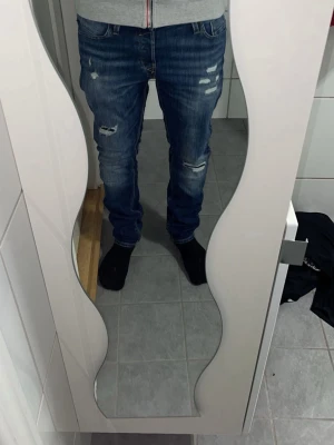 Jack and Jones jeans  - Säljer ett par blåa Jack and jones slimfit jeans med snygga slitningar. Storleken är 30/32 och killen med jeansen på är 177cm och väger 70kg