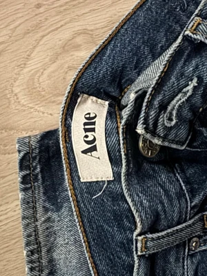 Mörkblå jeans från Acne - Snygga mörkblå jeans från Acne med klassisk femficksdesign och subtila slitningar på benen. Jeansen har raka ben och normal passform, tillverkade i robust denim med snygga kontrastsömmar. Perfekta för dig som gillar stilrena och tidlösa jeans, typ helt oanvända. W32 L30