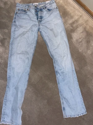 Ljusblå raka jeans från Zara - Ljusblå jeans från Zara med klassisk femficksmodell och raka ben. Jeansen har hög midja, knappgylf och rå kant upptill i midjan för en avslappnad vibe. Tillverkade i slitstarkt bomullsmaterial och har en vintageinspirerad tvätt.