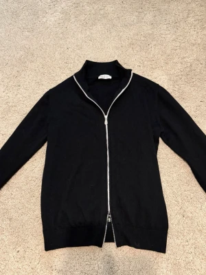 Svart cardigan jacka från Brunello Cucinelli - Säljer en svart full zip-cardigan från Brunello Cucinelli i cashmere. Klassik design med ribbade detaljer, i väldigt bra skick. Nypris cirka 2800euro. Inga kvitton kvar. Välkomnar seriösa prisförslag