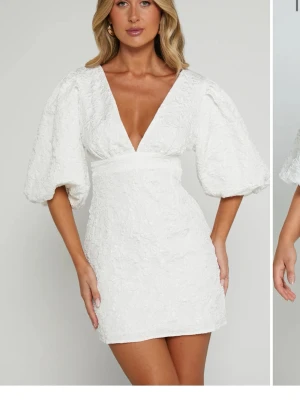 Söker denna klänning från showpo  - Supersnygg vit kort klänning med djup v-ringning och puffiga trekvartsärmar. Klänningen har en strukturerad yta och markerad midja som ger en riktigt trendig siluett. Perfekt för dig som vill sticka ut med en stilren look.