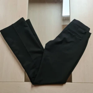 Populära lågmidjade kostymbyxor  - Svarta kostymbyxor från Bik Bok i klassisk modell som är lågmidjade med raka ben och pressveck. Byxorna har hällor för bälte, två fuskbakfickor och stängs med dragkedja och knapp. Perfekta för en clean och stilren look. Modellen Vera