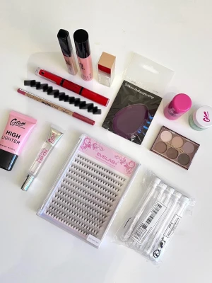 Smink-kit med läppglans, lösögonfransar, highlighter mm - Ett kit med en massa sminkartiklar!  1. En ”sminksvamp” i gummi 2. En mini skimrig ögonskuggspalett med  3. En highlighter på tub från Glam of Sweden 4. En lip oil från Glam of Sweden 5. Lösögonfransar (20D-0.05C MIX) 6. Got2b ”Farewell Flyaways” 7. Lip scrub från Glam of Sweden (Green apple) 8. Läppenna från Technic 9. Dubbelsidigt läppglans från NYX (Rebel in Red) 10. Glam of Sweden concealer i färgen ”Sand 10” 11. Glittrigt läppglans från NA-KD 12. Lip- and cheek tint - jelly 13. Spoolies frå