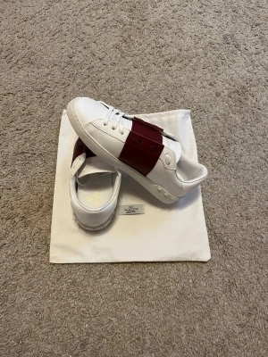 Vinröda unika skor - Säljer ett par helt nya skor i färgerna vinröd och vit. Skorna är i storleken 42 men skulle säga att de passar 43. Skick 10/10, dustbagen och självaskorna följer med😇.