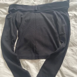 Svart offshoulder långärmad topp - Snygg svart offshoulder topp med långa ärmar och croppad passform. Perfekt för dig som vill ha en stilren och enkel look med en twist. Mjuk och stretchig känsla, passar till många outfits.