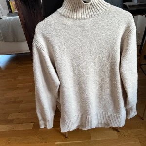 Beige stickad polotröja med slits - Säljer en oversized beige stickad polotröja med ribbad hög krage och breda muddar. Tröjan har långa ärmar och en snygg slits i sidan. Storlek XS, aldrig använd utav mig. Slutsåld på hm hemsida💗