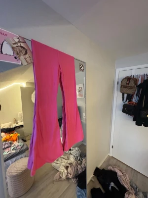 Rosa bootcut byxor i mjukt tyg - Säljer ett par riktigt snygga rosa bootcut byxor i mjukt och stretchigt material. De har hög midja och en clean look utan fickor eller dragkedjor. Perfekta för dig som vill sticka ut med färg och gillar bekväma plagg.