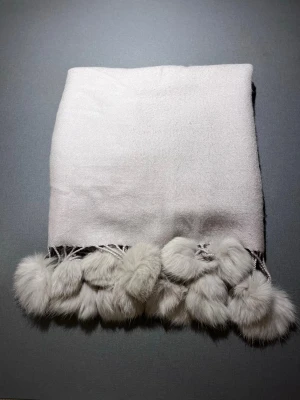 Beige sjal med pälsbollar - Mysig beige sjal med fluffiga pälsbollar längs kanten. Sjalens material är mjukt och har en lätt glans, vilket ger en lyxig känsla. Pälsbollarna är täta och ger en extra touch av stil. Perfekt att slänga över axlarna för en trendig look. 100% Viskos. 180x70. Exceptionellt skick, som ny! Säljs på flera sidor, först till kvarn. 