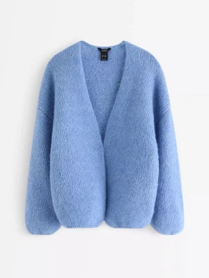 Blå stickad kofta från Lindex - Mysig blå stickad kofta från Lindex med oversized passform och långärmade ärmar. Koftan har en djup v-ringning och är tillverkad i ett mjukt material som ger en fluffig känsla. Perfekt att slänga på sig när det är kyligt ute.