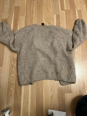 Mörk Beige stickad kofta från Lindex - Mysig mörk beige stickad kofta från Lindex i storlek XS/S. Koftan har långärmade ärmar och är öppen framtill utan knappar eller dragkedja. Perfekt att slänga på sig när det är lite kyligt ute. Materialet känns mjukt och har en lite loose passform.