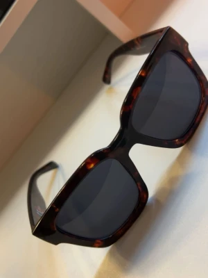 solgalsögon😎 - Kaws är ​en tidlös klassiker från​A.Kjærbede. Perfekta solglasögon, med alla detaljer man kan önska sig. Modellen har både runda och skarpa kanter. De diskreta men samtidigt iögonfallande solglasögonen är knappast små, men inte heller oversize. En modell att alltid återvända till.  Specifikationer:  UV 400-filter. Polykarbonatlinser. Optiska gångjärn av hög kvalitet. Rengöringspåse ingår. Formbara skalmar med metallkärna. Lins: 50 mm. Bro: 22 mm. Skalmar: 145 mm.