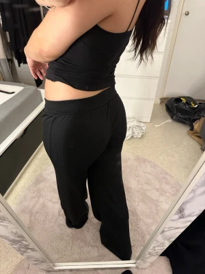 Svarta vida ribbade byxor - Säljer ett par svarta vida byxor med ribbad struktur och resår i midjan. De har en loose fit och är riktigt sköna att ha på sig, perfekta för en chill och avslappnad stil. Materialet känns mjukt och stretchigt.obs fina små lösa trådar längst ner
